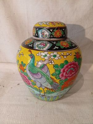 un vase jaune orné d'un oiseau sur fond blanc