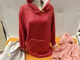 un sweat à capuche rouge posé sur une table où se trouvent d'autres vêtements