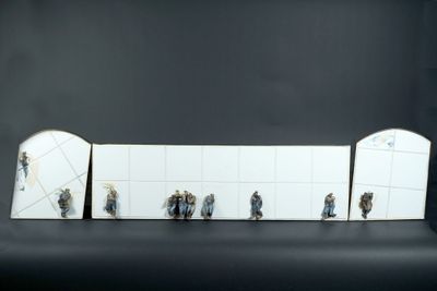 a group of figurines of people standing in front of a wall