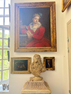 a statue of a woman in a red dress in front of a painting