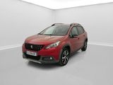 Une voiture rouge est garée dans une pièce blanche