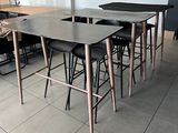 tables and stools in a room with a white wall and tile floor