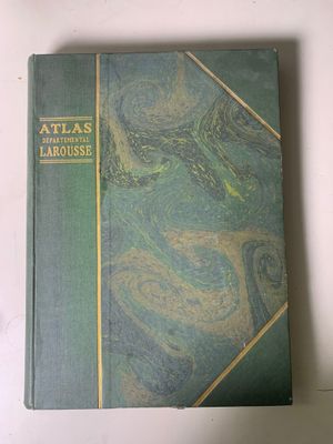 un vieux livre à la couverture verte posé sur une table blanche