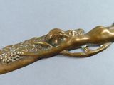 a bronze sculpture of a woman laying on a branch of a tree