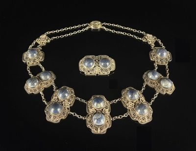 a close up of a necklace and earrings on a black background