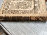 an old book sitting on a table with a clock on it