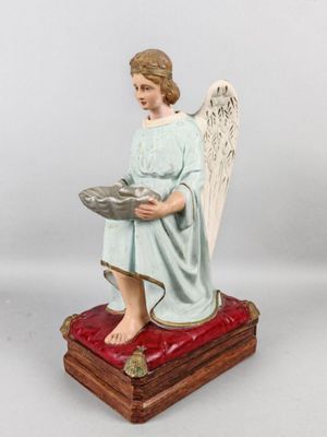 une image représentant une statue d'ange assis sur un coussin rouge