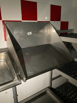 un évier en acier inoxydable dans une cuisine dont les murs sont recouverts de carrelage rouge et blanc
