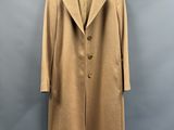 un manteau beige suspendu à un cintre devant un mur gris
