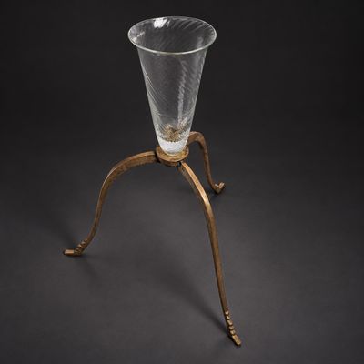 un vase ancien en verre posé sur un socle à base métallique