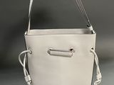 a white bucket bag with a metal handle and a white cord