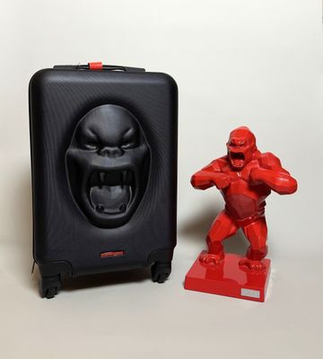 a red toy and a black suitcase on a table