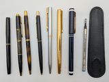 several pens and pencils are lined up on a white surface