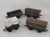Trois wagons de train miniature sont alignés sur une surface blanche.