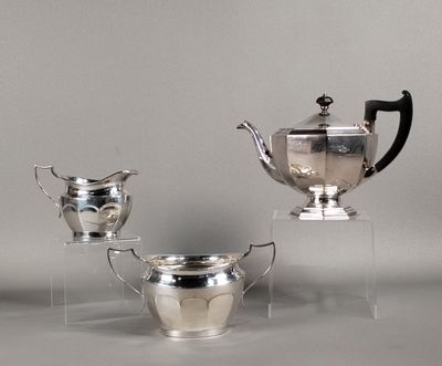 trois théières en argent et deux tasses en argent posées sur un présentoir