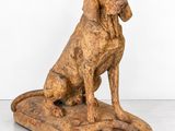une vieille statue en bois représentant un chien assis sur un bloc de bois