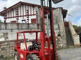 a red fork lift truck parked in front of a building