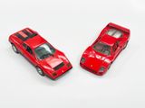two red toy cars sitting next to each other on a white surface