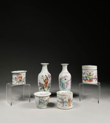 Plusieurs vases et tasses sont posés sur une table devant un fond noir.