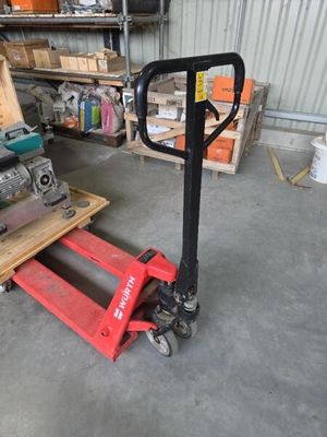 une photo d'un chariot élévateur dans un entrepôt, avec des palettes et des cartons