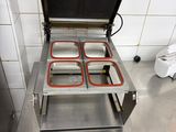 stainless steel counter top with four trays of food in a commercial kitchen