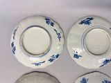 three blue and white plates and a bowl on a white surface