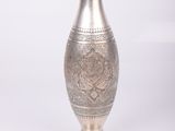 a silver vase that is sitting on a white surface