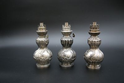 trois vases en argent posés sur une table, sur fond noir