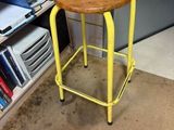 a yellow stool with a wooden seat in a room