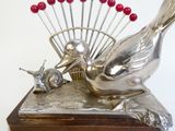 une sculpture en argent représentant un oiseau et un escargot posée sur une table