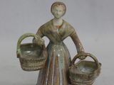 une figurine représentant une femme tenant deux paniers