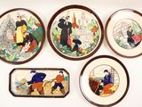 quatre assiettes décoratives sur lesquelles sont représentées des personnes, sur un fond blanc