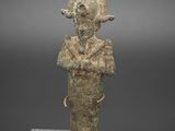 une ancienne statue en bronze représentant un homme coiffé d'un chapeau
