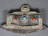 une vieille broche en argent et turquoise, ornée de pierres rouges et bleues