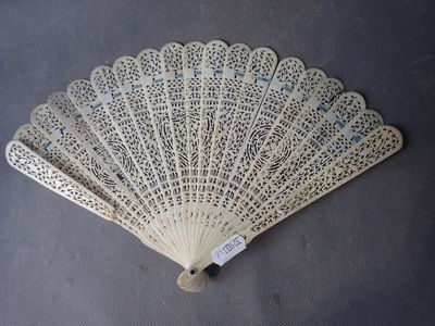un éventail en dentelle blanche posé sur une table, avec une étiquette accrochée dessus