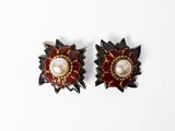 paire de boucles d'oreilles rouges et dorées ornées de perles sur fond blanc