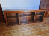 a wooden entertainment center with glass doors and shelves