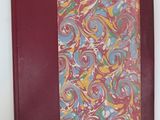 an old book with a red cover and a colorful swirl pattern on it