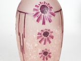 a pink vase with purple flowers on it on a white surface