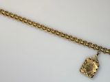 Gros plan sur un bracelet en chaîne en or sur lequel se trouve une pièce de monnaie