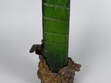 a green glass vase with a gold base on a table