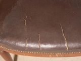 a close up of a brown leather chair with holes in the seat
