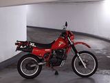 a red motorcycle parked in a parking garage next to a white wall