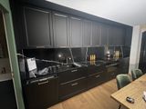 une photo d'une cuisine avec des placards noirs et une table en bois
