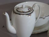 a white tea pot sitting next to a bowl and a plate