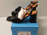 Sur la boîte à chaussures, on voit une paire de sandales noires.
