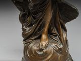 bronze statue of a woman holding a bird on a pedestal