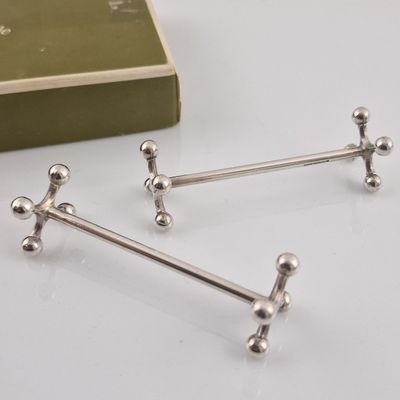 three silver metal handles on a white surface next to a book