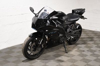 une moto noire garée dans une pièce au sol en damier