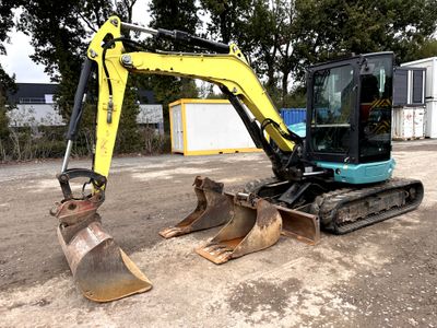 a yellow and blue excavator sitting on the dirt